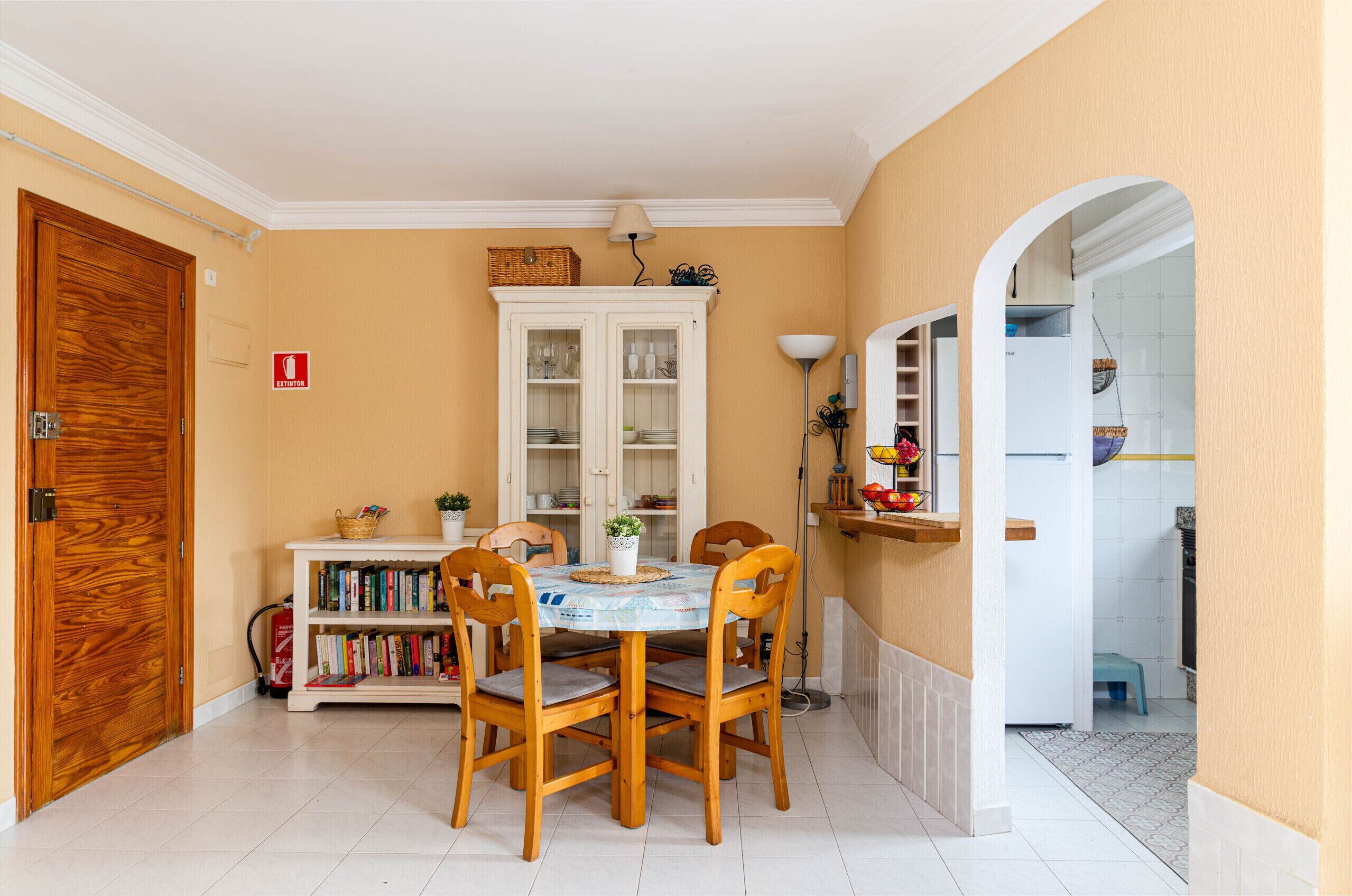 A dining area with a round table, four chairs, a bookshelf, and a cabinet.