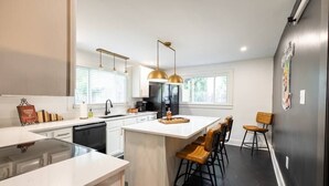 A modern kitchen with white cabinetry, a central island, and pendant lighting. - “Bourbon Trail Beauty” (Lawrenceburg)