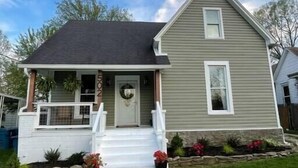 A two-story house with a front porch, a small front yard, and a clear sky. - “Bourbon Trail Beauty” (Lawrenceburg)