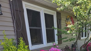 A house with a window, a brick border, and a garden with green and pink plants. - Vacation home near the beaches!. (Pocomoke City)