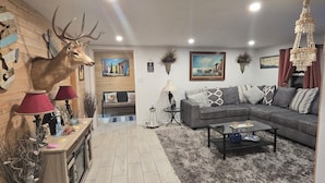 A living room with a sofa, coffee table, and a mounted deer head. There is a fireplace, a chandelier, and a painting on the wall. - Vacation home near the beaches!. (Pocomoke City)