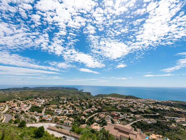A coastal town with a mix of residential buildings and open spaces, a clear sky, and a view of the sea.