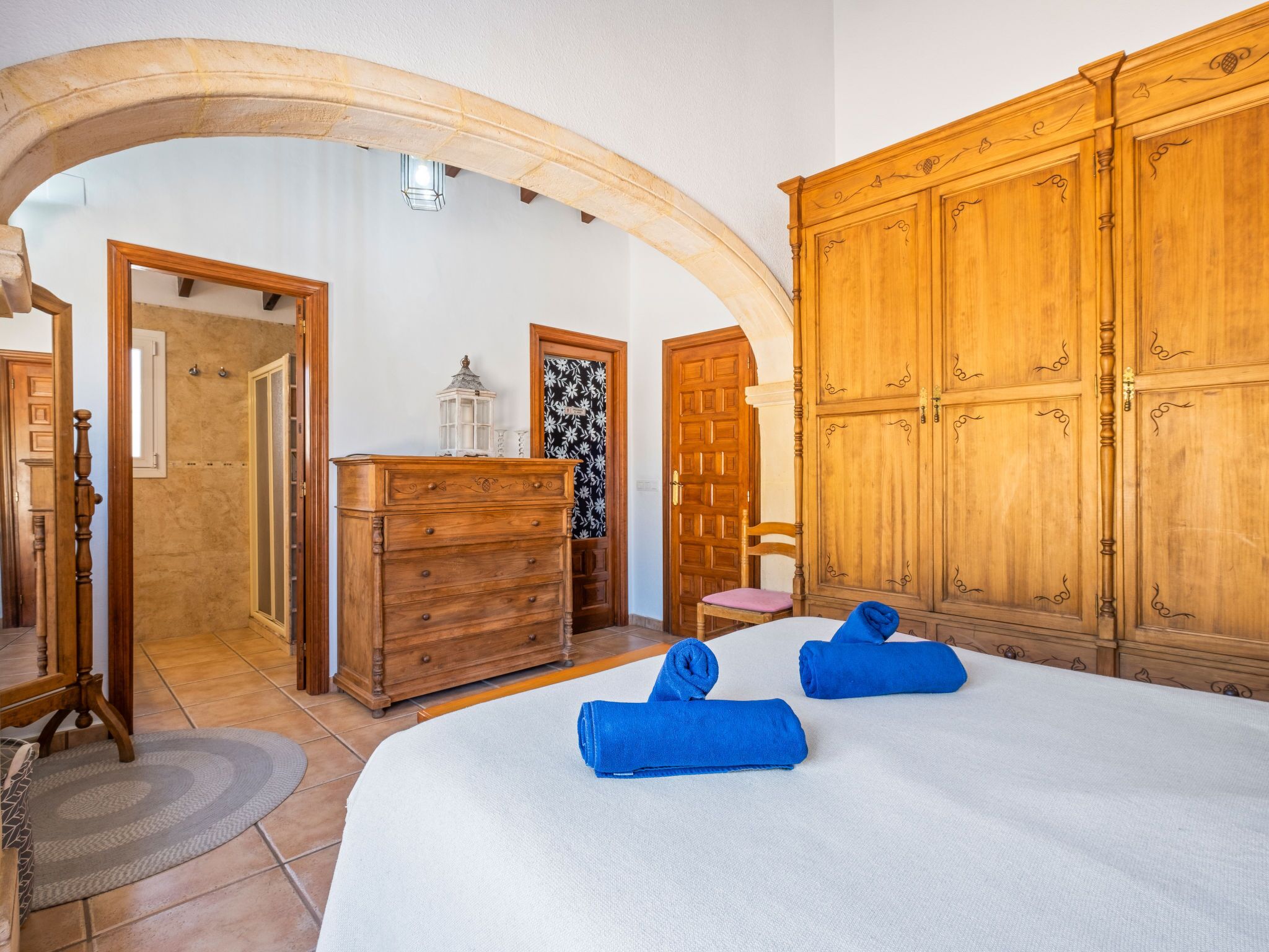 A bedroom with a large bed, wooden wardrobe, and a dresser.