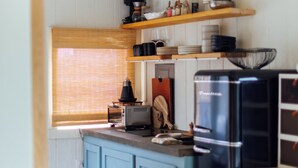 Una cucina con mobili azzurri, un frigorifero nero e mensole in legno sopra.
