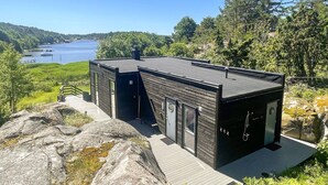 A modern cabin with a deck, large windows, and a view of a lake. - Awesome home in Skjærhalden (Skjærhalden)