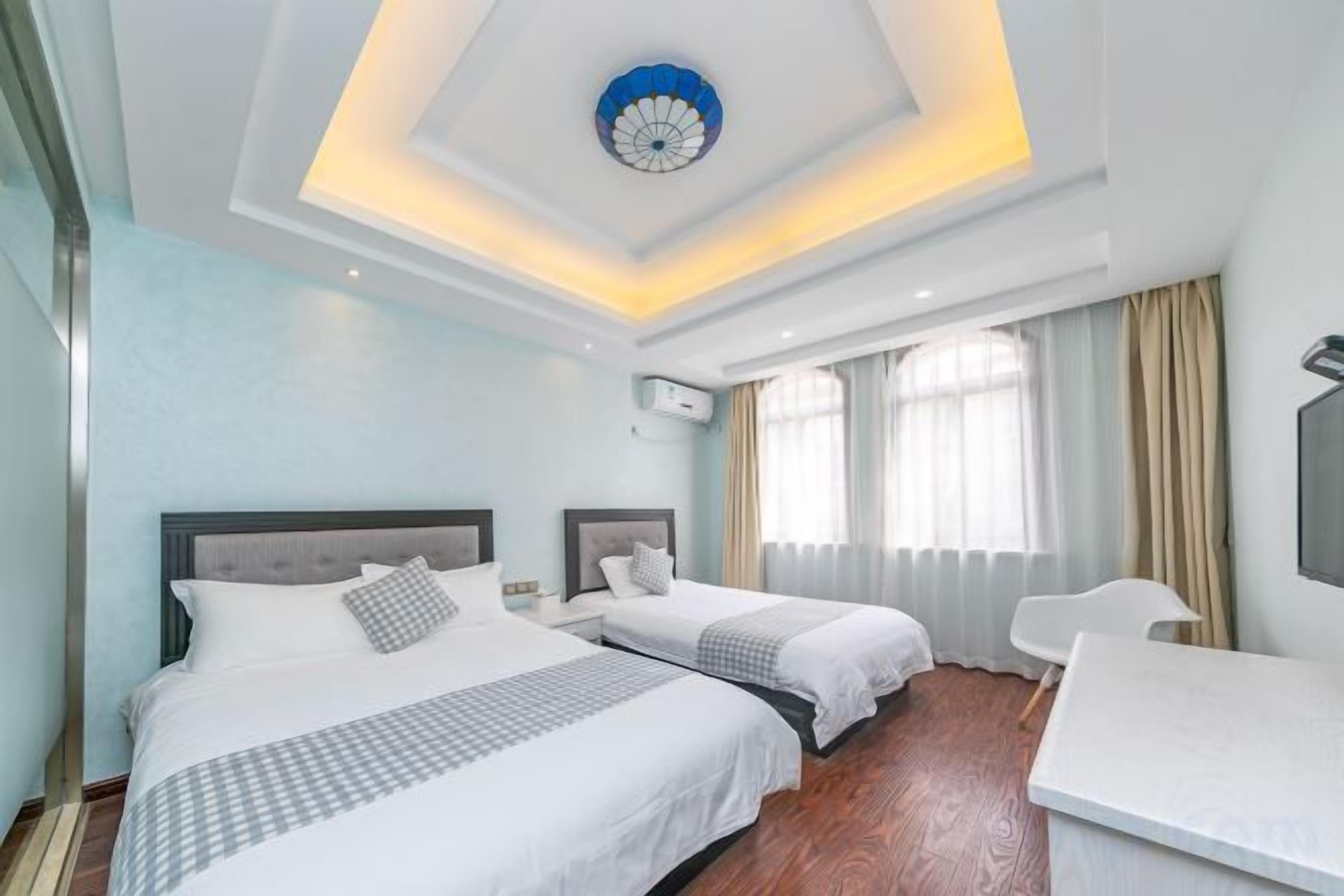 Ein Hotelzimmer mit zwei Betten, einem Schreibtisch und einem großen Fenster mit Vorhängen.