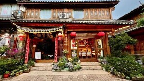 A traditional building with a tiled roof, wooden doors, and a small garden area with potted plants. - Juxian Boutique Homestay（South Gate of Ancient City） (Lijiang)