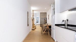 Une cuisine moderne avec des armoires blanches, un comptoir noir et un four encastré. On y trouve également un coin repas avec une table et des chaises en bois.