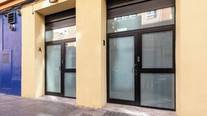Une façade d’immeuble avec deux portes vitrées, une porte bleue à gauche et un mur jaune.