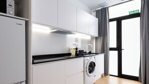 Une cuisine moderne avec des meubles blancs, un plan de travail noir, un lave-linge encastré et un évier.