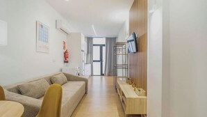 A modern living room with a sofa, a wooden coffee table, and a TV mounted on the wall. - VLC HOST - San Jacinto A (Valencia)