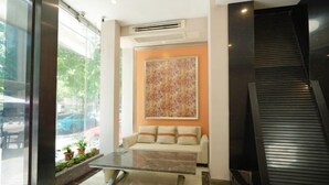 A modern lobby with a glass partition, a sofa, a marble coffee table, and a staircase.