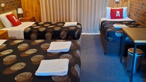 Quarto de hotel com duas camas, uma mesinha e uma cadeira.