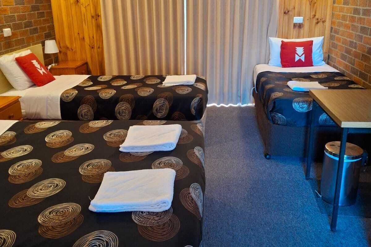 A hotel room with two beds, a small table, and a chair.