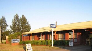 Um motel com um letreiro indicando 'VACANCY', um letreiro 'MOTEL' e um letreiro 'GUESTS ONLY'.