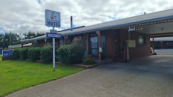 A motel with a 'VACANCY' sign, a covered parking area, and a brick building.