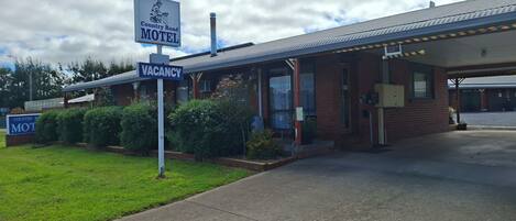 A motel with a 'VACANCY' sign, a covered parking area, and a brick building.