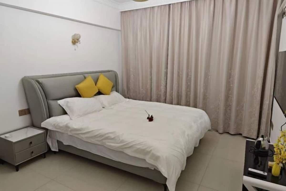 Un dormitorio ordenado con cama, mesita de noche y velador.
