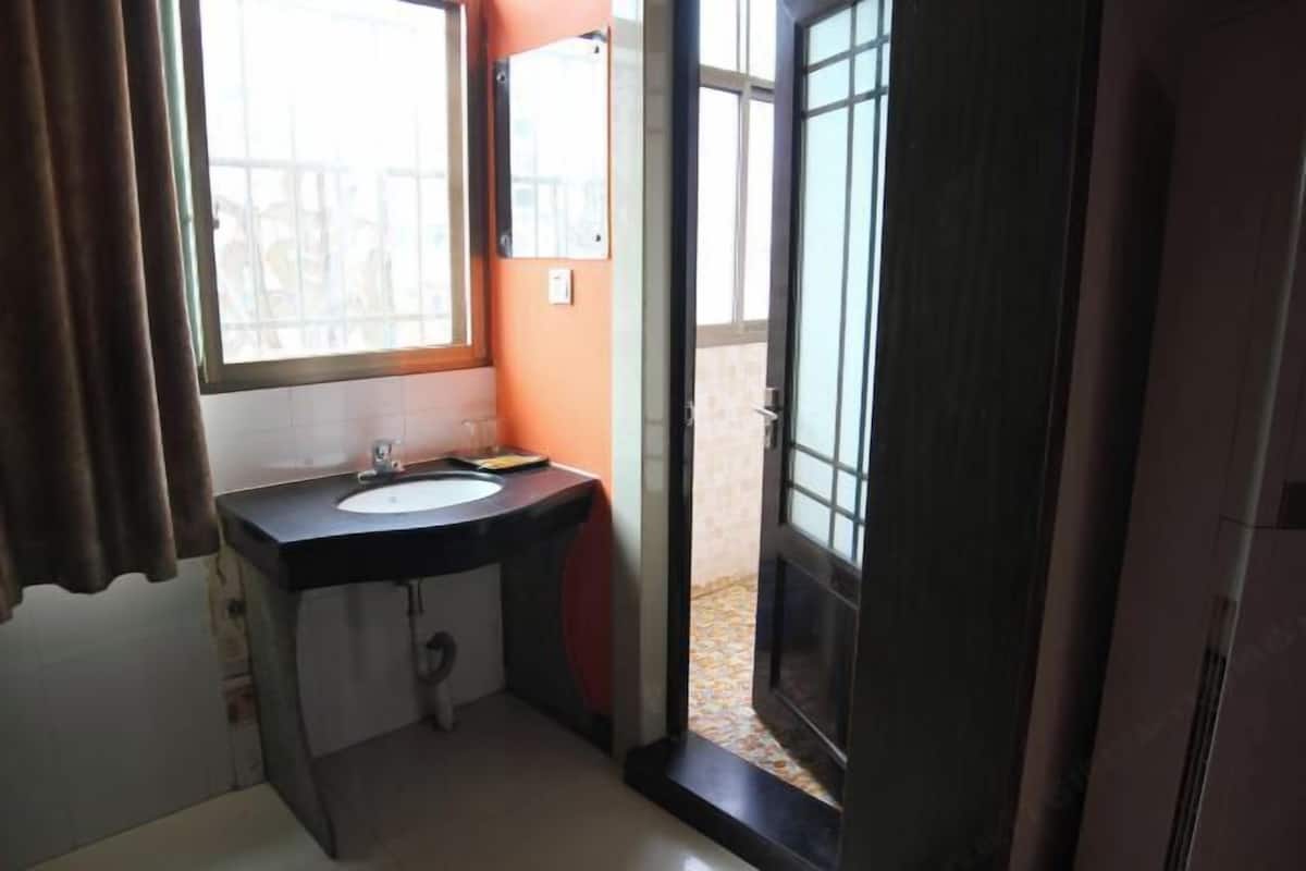 Un baño con lavamanos, espejo y vistas a un espacio exterior a través de una puerta abierta.