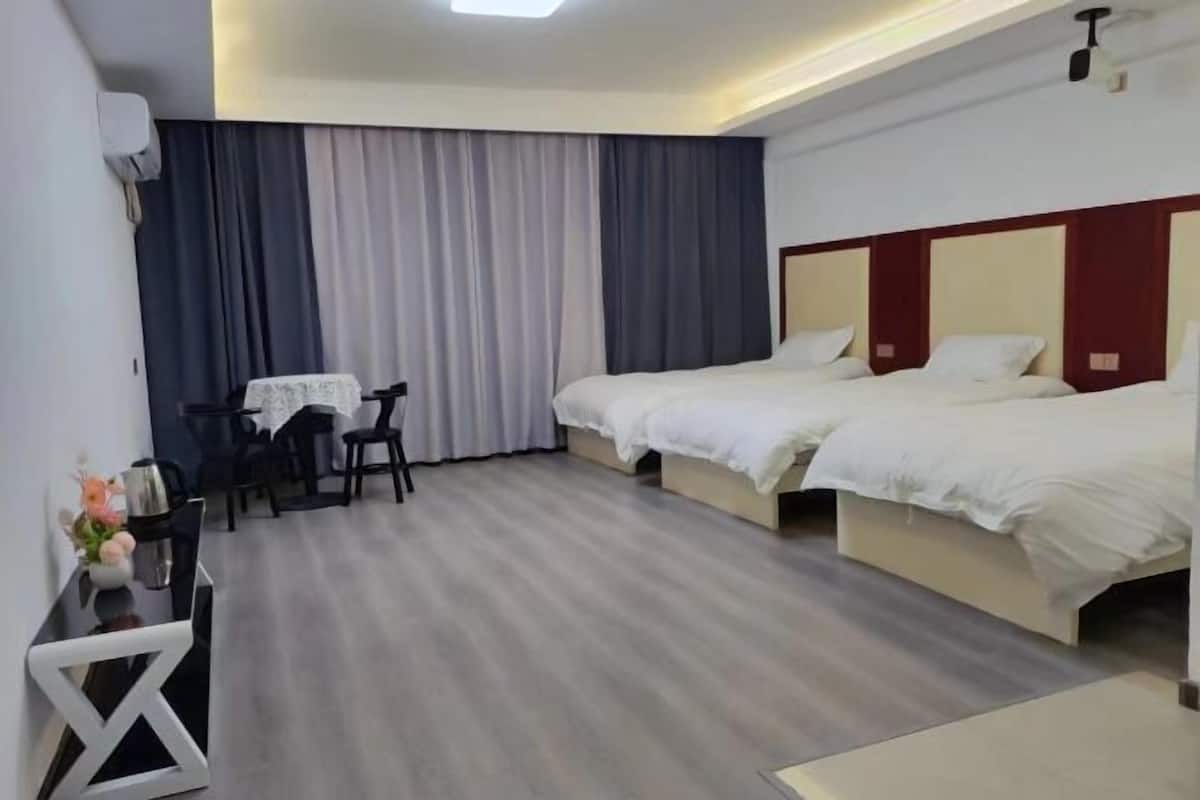 Una habitación de hotel con dos camas, un escritorio con una silla y una mesita con un jarrón de flores.
