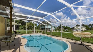 Una piscina cubierta con sillas de descanso y una mesa de vidrio, rodeada por una estructura de armazón blanco.