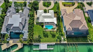 Vista aerea di una zona residenziale con case moderne, una piscina e un porto turistico.