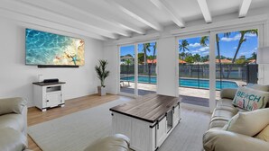Un ampio soggiorno con una grande finestra vista piscina, un tavolino in legno e un divano confortevole.