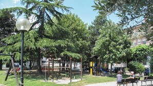 Ein Park mit einem Spielplatz, Bänken und einem gepflasterten Weg.