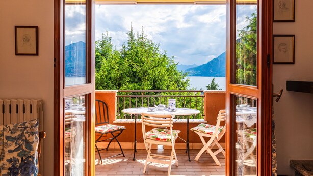 Ein Balkon mit Tisch und Stühlen, einem Heizkörper und gerahmten Bildern an den Wänden.