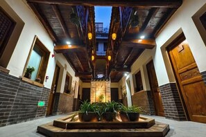 Un couloir avec un plafond en bois, des plantes en pot et un luminaire central.
