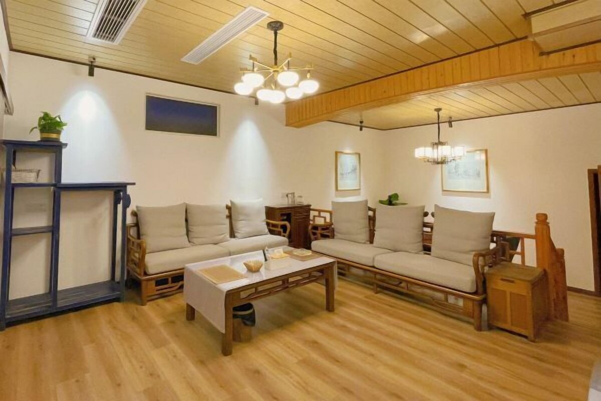 A cozy living room with a wooden floor, two sofas, a coffee table, and a bookshelf.