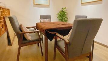 Uma área de refeições com mesa de madeira e quatro cadeiras, uma planta e quadros nas paredes.
