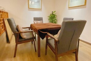 A dining area with a wooden table and four chairs, a plant, and framed pictures on the wall.