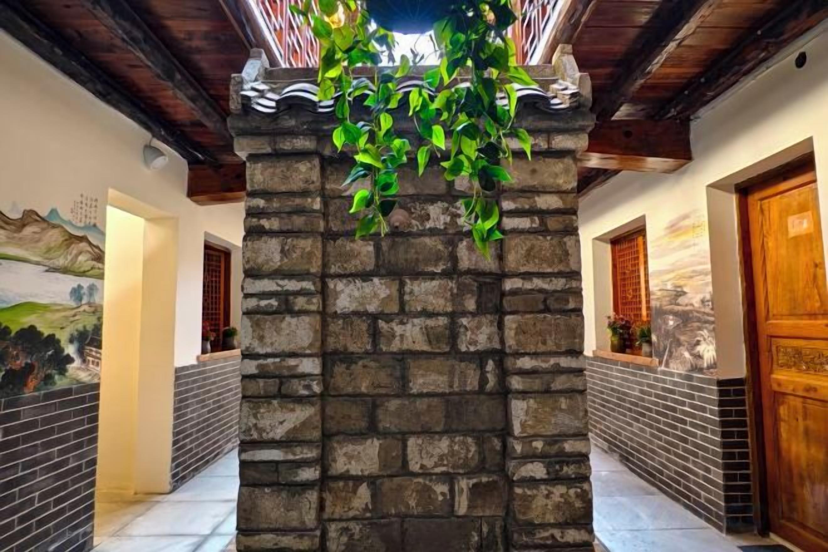 Pared de piedra con plantas colgantes, puertas de madera y suelo de baldosas en un pasillo.