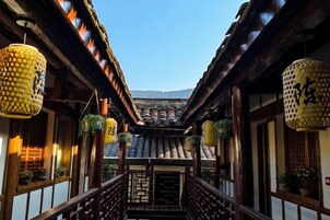 Un pasillo tradicional japonés con barandales de madera y faroles colgantes.