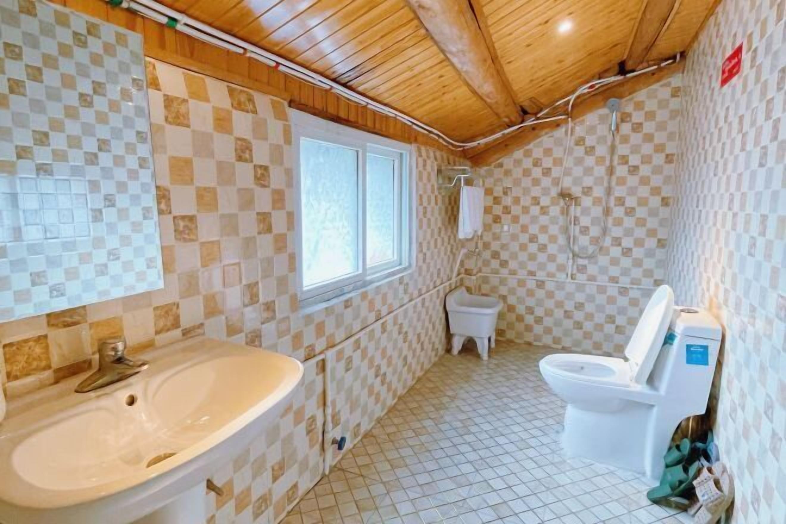 Ein Badezimmer mit Schachbrettfliesen, einem Waschbecken, einer Toilette und einem Fenster.