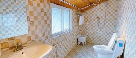 A bathroom with a checkered tile design, a sink, a toilet, and a window.