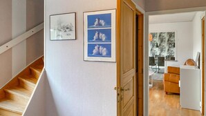 A staircase leading to a room with a wooden door, a dining area with a table and chairs, and three framed photographs on the wall. - 5 bedroom amazing home in Tingsryd (Tingsryd)