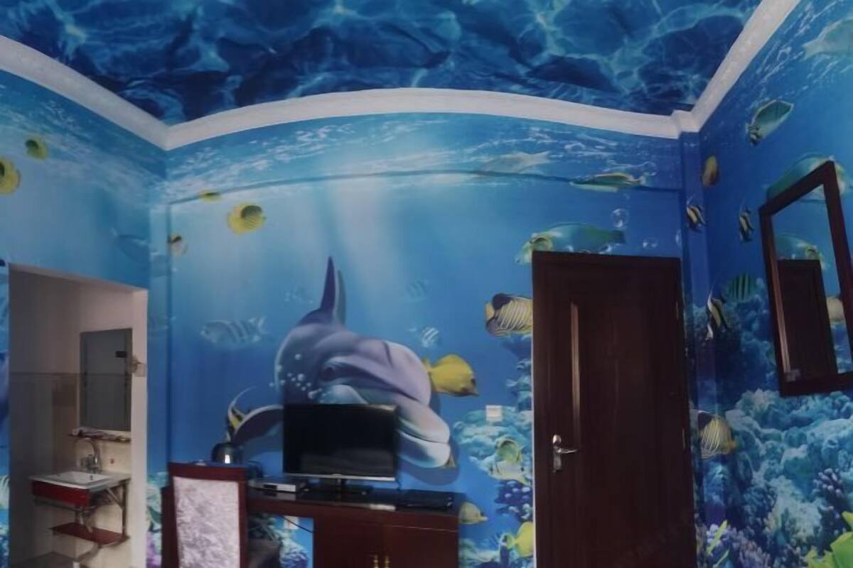 Een kamer met een muurschildering van de blauwe oceaan, een televisie en een houten deur.