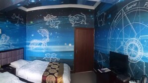 Une chambre avec un lit, un bureau et un mur décoré de signes du zodiaque et de constellations.