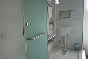 Een badkamer met toilet, hygiëneschuimer en douche.
