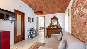 A living room with a brick ceiling, a sofa, a wooden dresser, and a sewing machine. - Apartment Giada by Interhome (Castell' Alfero)