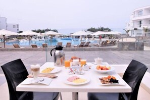 Et morgenbord med tallerkener med mad, en kaffepotte og et glas appelsinjuice.