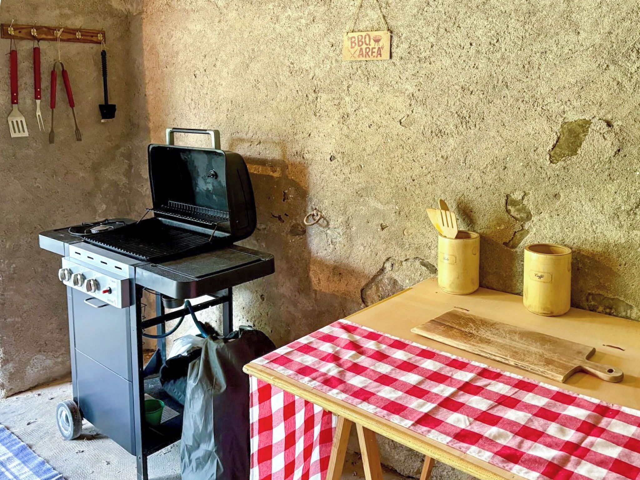 Keittiö, jossa on kannettava grilli, ruutukuviollinen pöytäliina ja kyltti, joka osoittaa grillausalueen.