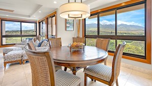 Un comedor con una mesa redonda, sillas y vistas a un paisaje a través de grandes ventanales.