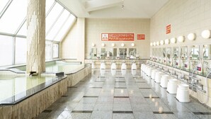 A modern restroom with multiple sinks, a large pillar, and a tiled floor. - Asahi Sauna Capsule Inn Hirosaki (Hirosaki)