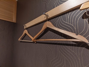 A wooden coat rack with a simple design, mounted on a wall with a textured pattern. - Asahi Sauna Capsule Inn Hirosaki (Hirosaki)