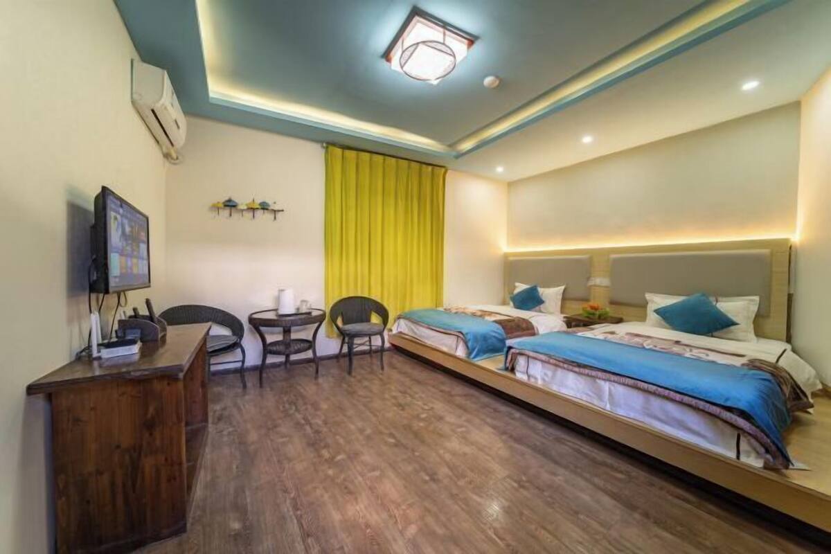 Habitació d'hotel amb escriptori de fusta, dos llits individuals, una taula petita i una televisió.