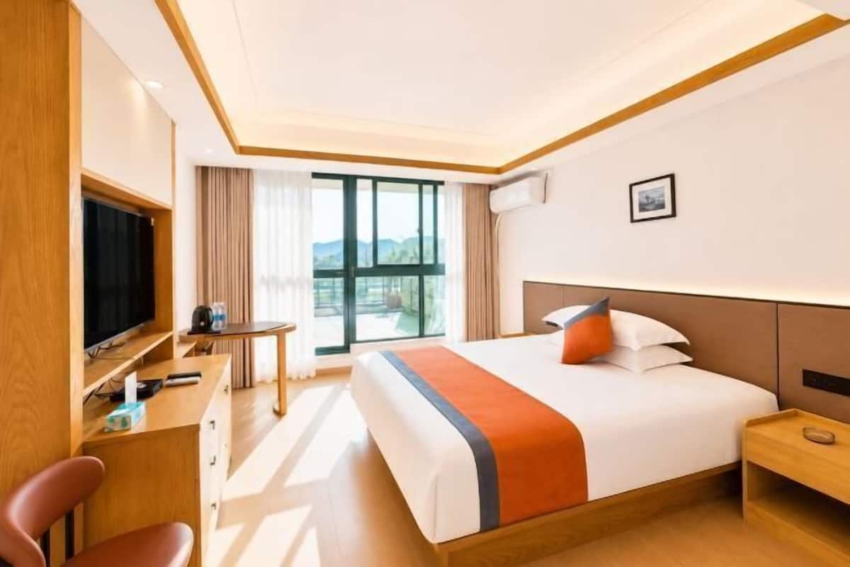 Ein Hotelzimmer mit Bett, Schreibtisch, Fernseher und Fenster mit Blick.