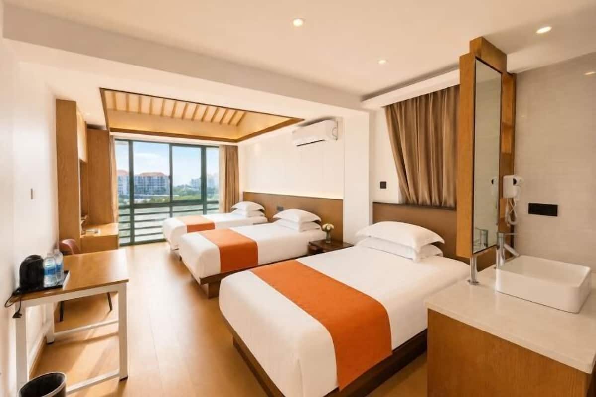 Ein Hotelzimmer mit zwei Betten, einem Schreibtisch, einem großen Fenster und einem Badezimmer.
